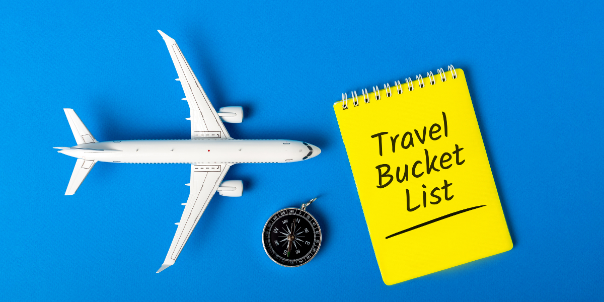 airplane toy on a blue background next to a sticky note with travel bucket list on it