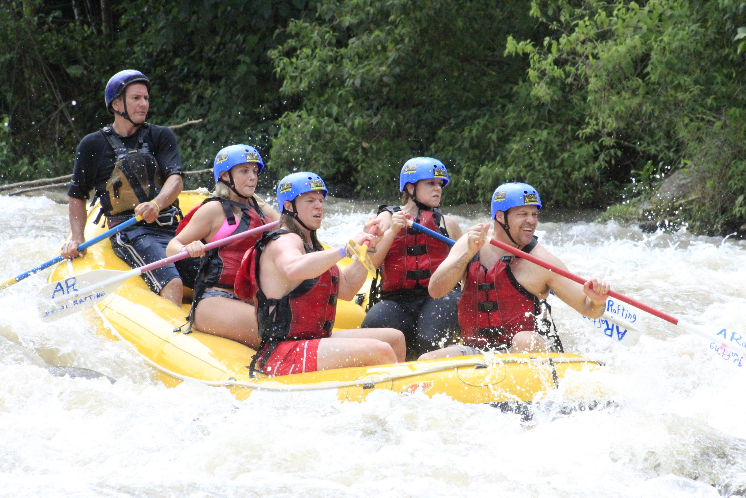 a group of 5 people on a yelloow raft in a river in Costa Rica 